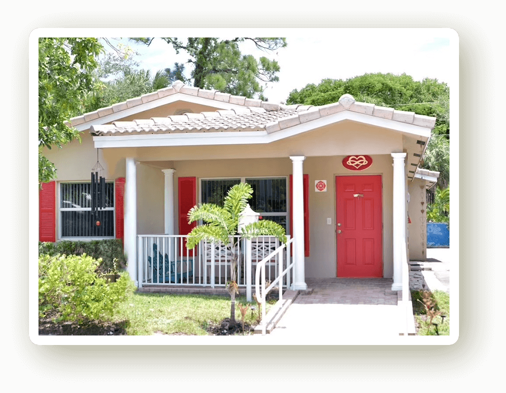 The front of Healing Hive House, a house with red doors and white porch rails